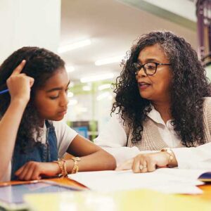 A teacher working with a student at a desk.